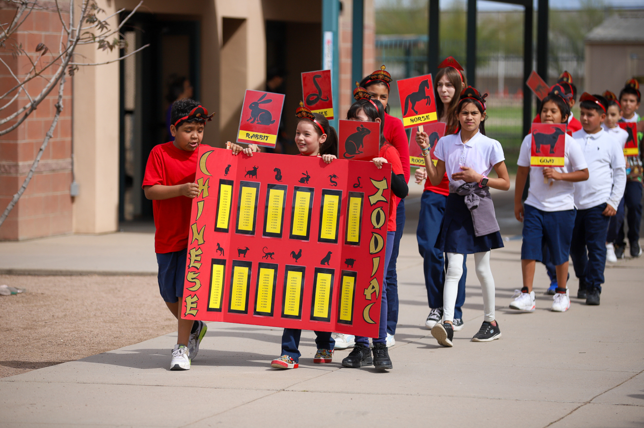 Students parade out carrying a poster with the Chinese Zodiac on it