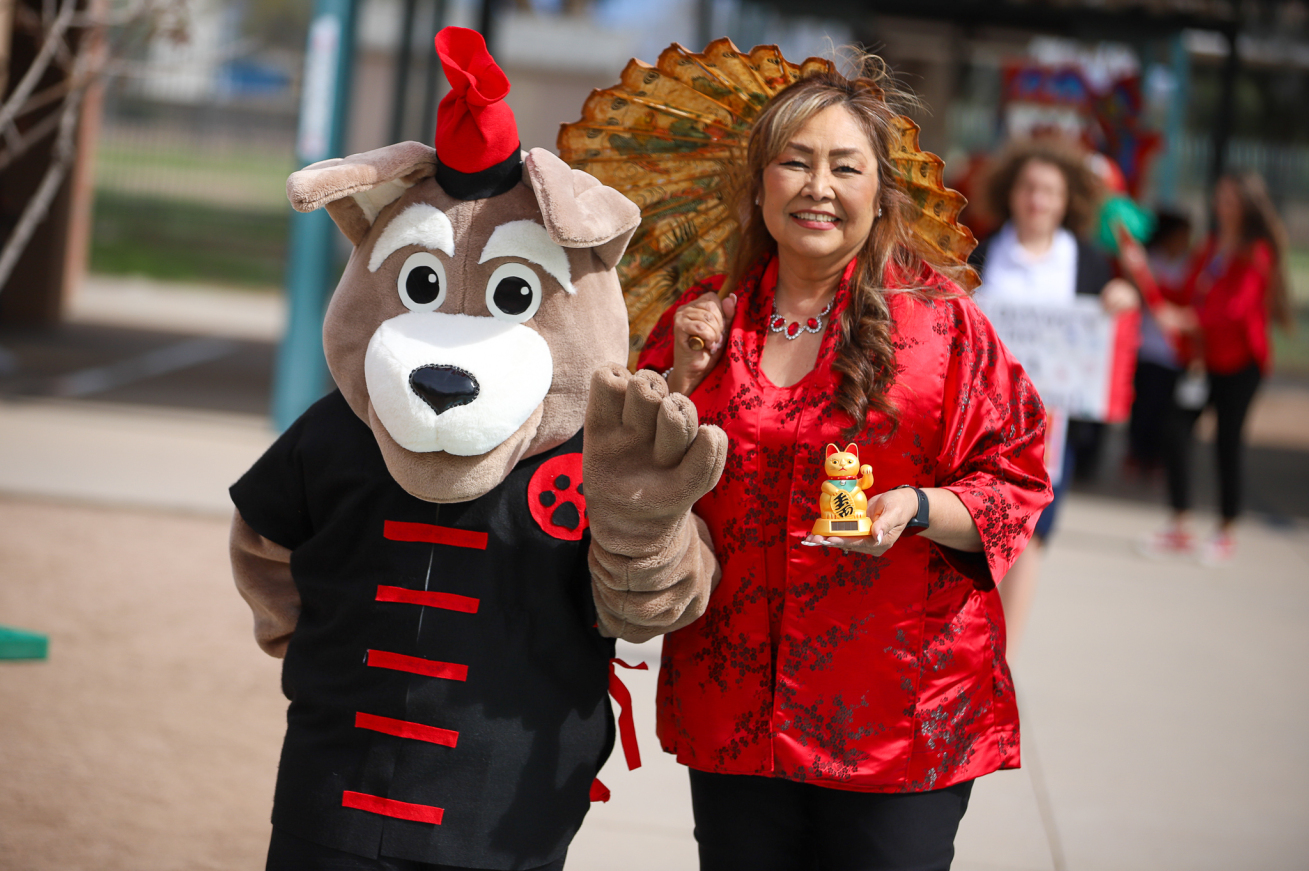 The school's mascot poses with a teacher in traditional Chinese clothing