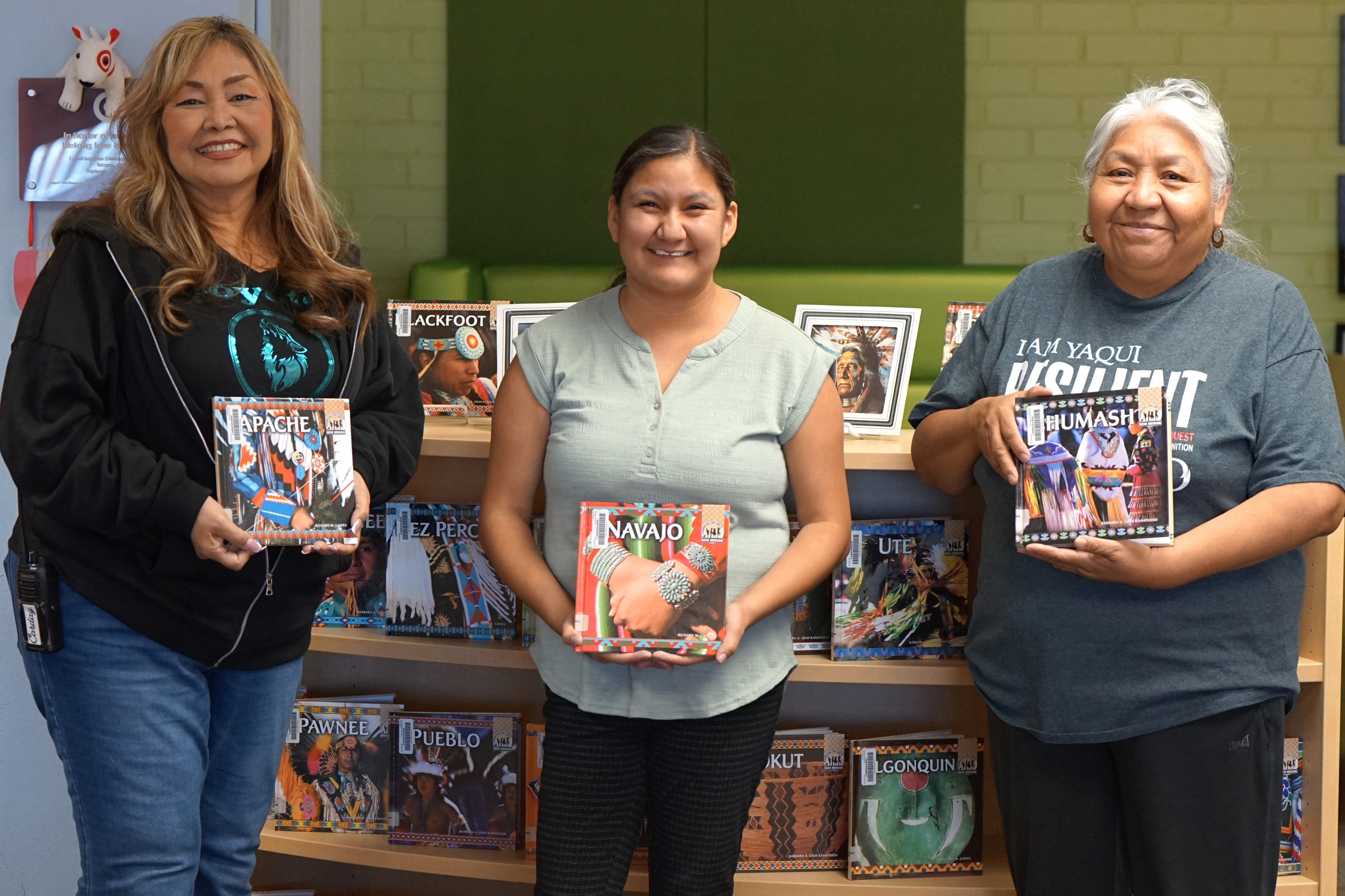 Three women display books about Native Americans