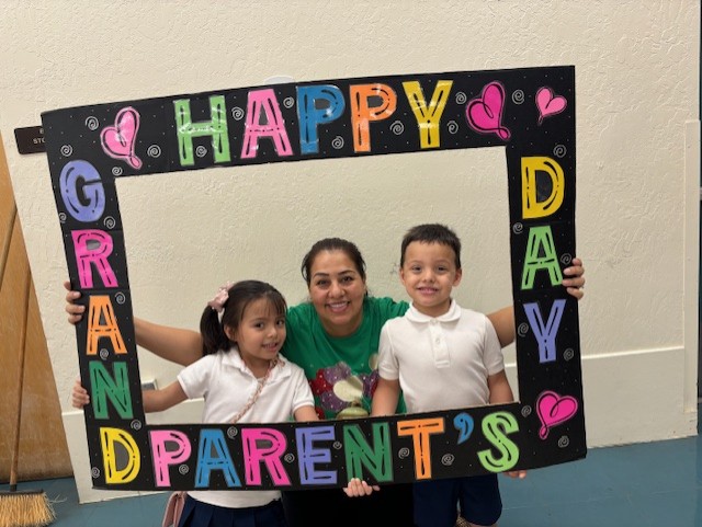 A girl and boy pose with their grandma in the Grandparents Day photo frame