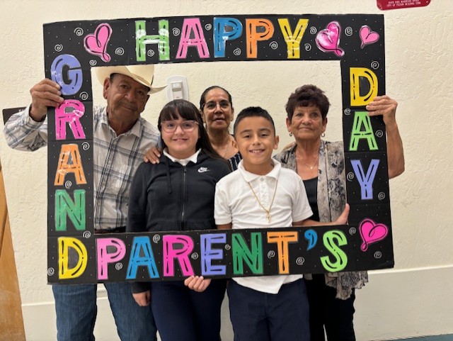 A girl and boy smile with their grandpa and grandmas in the Grandparents Day photo frame