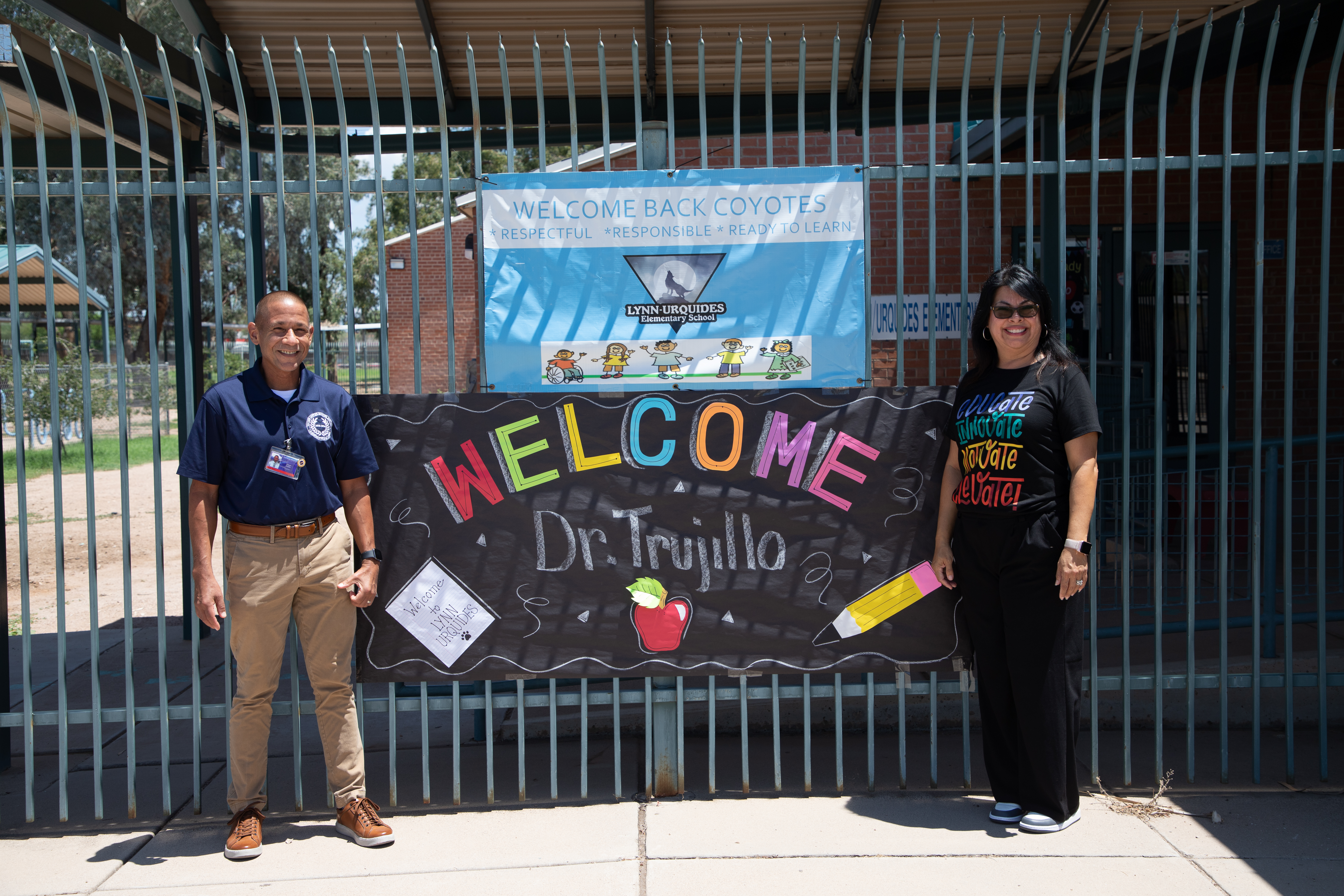 Dr. Trujillo and Lynn-Urquides' principal stand in front of a welcome banner