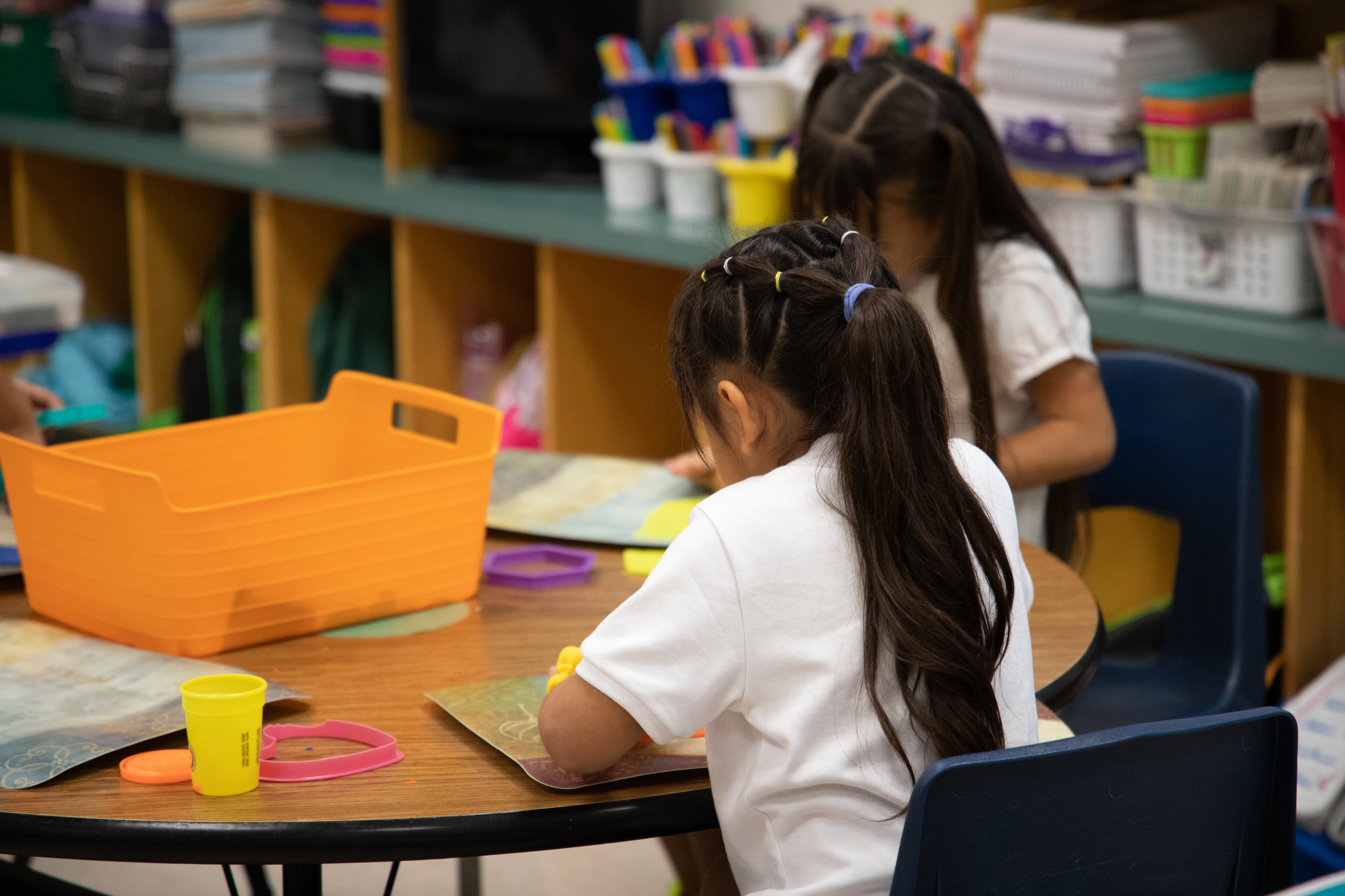 Two girls work on an art project at their desk