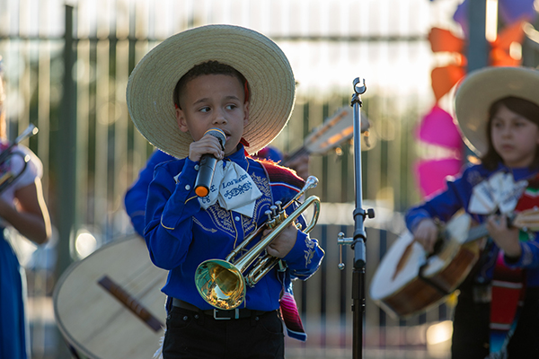 A little boy holding a trumpet sings into a microphone